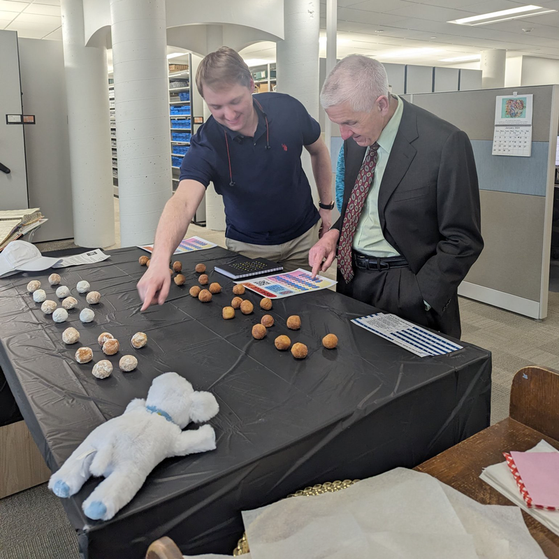 Josh Easter shows Secretary Joseph Graves the braille letters made from donut holes