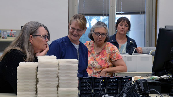 staff observing duplication on demand equipment