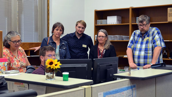 south dakota staff surrounding north dakota staff person at computer