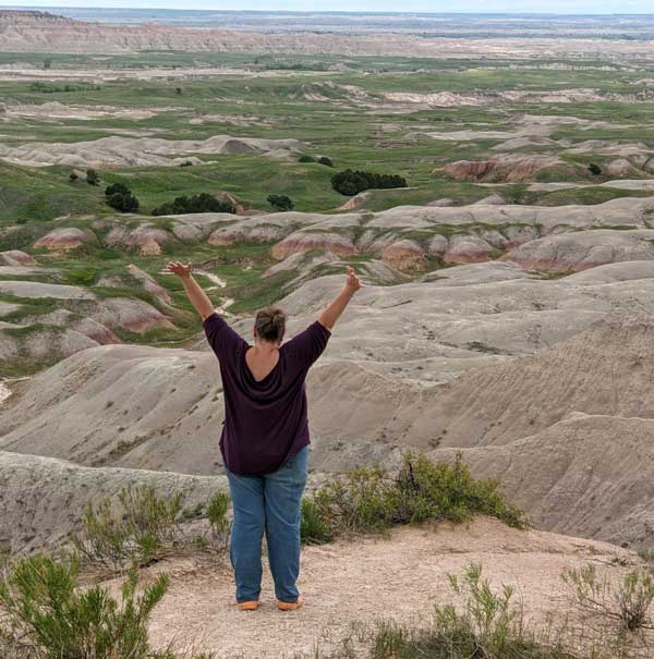 woman standing with arms up at the South Dakota Badlands