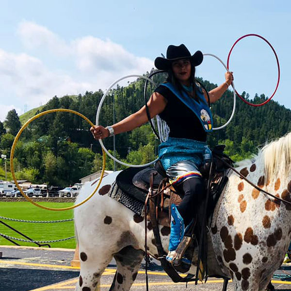 young native american woman riding horse and presenting hoops
