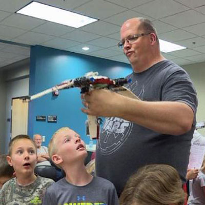 curtis mork showing LEGO set to kids, photo by Kelsey Dickeson, KSNB 2019