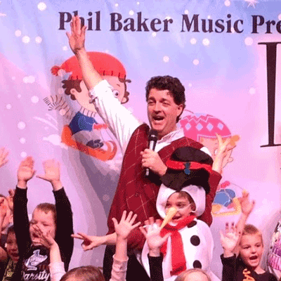 phil baker singing with kids in costume on stage
